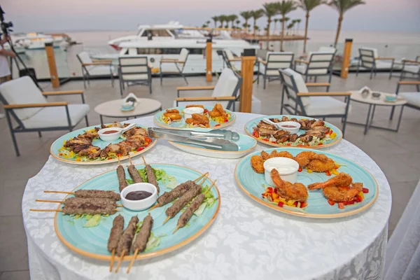 マリーナビューの豪華な屋外レストランビュッフェエリアでテーブルの上の肉料理とフィンガーフードの選択ディスプレイ — ストック写真
