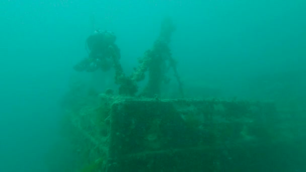 技術的なスキューバダイバーは 濁った水の中で大規模な水中沈没深い難破船の外弓に沿って泳ぐ — ストック動画