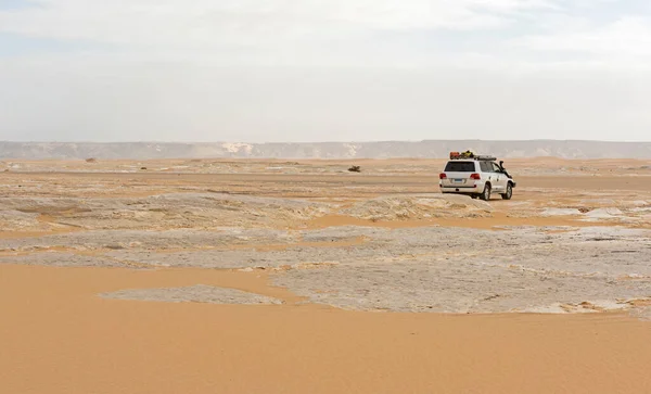 Landscape scenic view of desolate barren western desert in Panoramic barren landscape in Egypt Western White desert with overcast sky and 4x4 safari vehicle