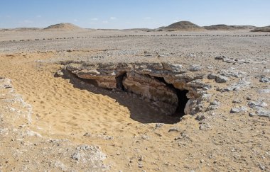 Landscape scenic view of desolate barren western desert in Egypt with rocky vista and entrance to underground Djara Cave