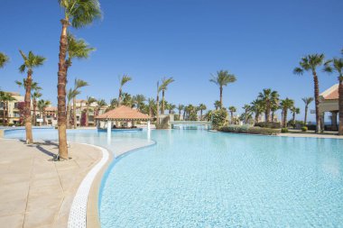 Large outdoor swimming pool at a luxury tropical hotel apartment resort in summer