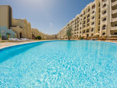 Large outdoor swimming pool at a luxury tropical hotel apartment resort in summer