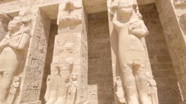 Luxor Mısır 'daki antik Mısır Medinat Habu Tapınağı' nda sütunlu hiyeroglif oymalar ve heykeller