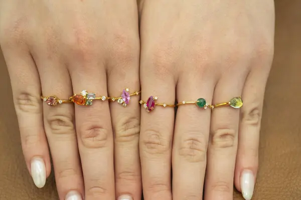 Selection of luxury expensive gold jewelry rings with gemstones on fingers of female womans hand