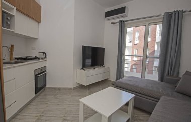 Lüks apartmandaki oturma odasının oturma odası ev dekorasyonunu gösteriyor. Açık mutfak ve balkonla döşenmiş.