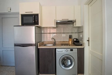 Lüks apartman galerisindeki modern küçük mutfak ve aletleri gösteren iç dizayn dekorasyonu.