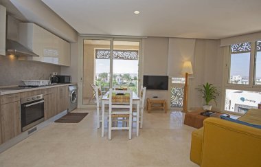 Lüks apartmandaki oturma odasının oturma odası balkon terası ve açık mutfak döşenmiş iç tasarım dekorasyonunu gösteriyor.