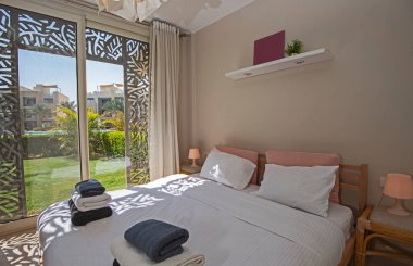 Lüks mobilyaların iç dizayn dekorasyonu ev yatak odasını gösteriyor ve bahçe manzaralı çift kişilik yatak.