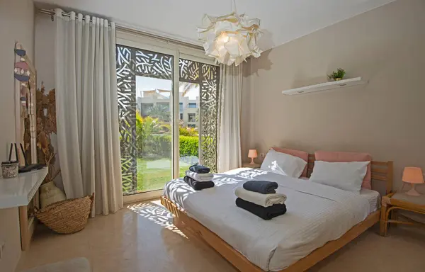 Interior design decor furnishing of luxury show home bedroom showing furniture and double bed with garden view