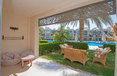 Tropikal tatil köyünde mobilya ve havuz manzaralı lüks bir apartmanın bahçe terası mobilyaları.