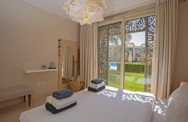 Lüks mobilyaların iç dizayn dekorasyonu ev yatak odasını gösteriyor ve bahçe manzaralı çift kişilik yatak.