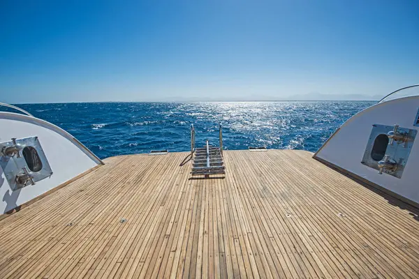 日落时分 一艘大型豪华游艇在热带海洋上航行 船背柚木甲板上的金属钢梯 — 图库照片