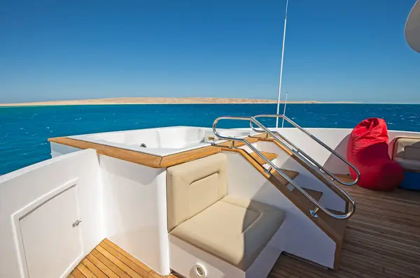 热浴缸和热带海景背景大型豪华游艇的精致弓形木制甲板 免版税图库图片
