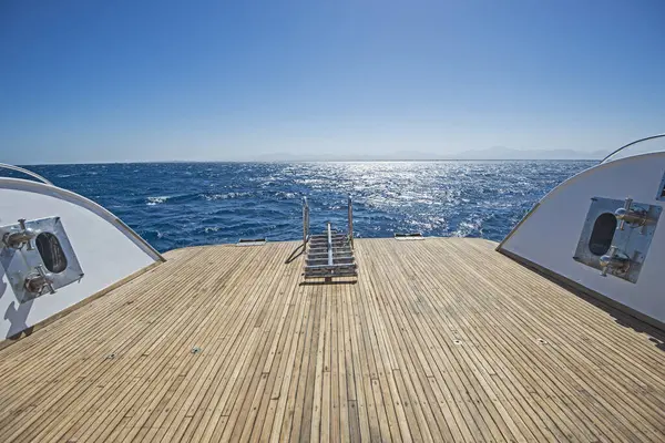 日落时分 一艘大型豪华游艇在热带海洋上航行 船背柚木甲板上的金属钢梯 图库照片