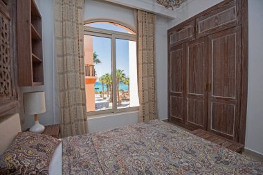 Lüks mobilyaların iç dizayn dekorasyonu ev yatak odasını gösteriyor ve tropikal deniz manzaralı çift kişilik yatak.