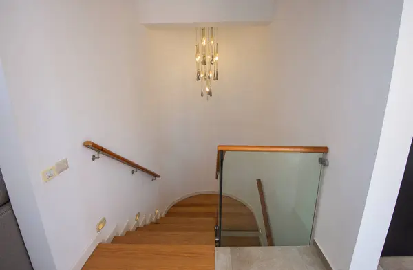 用吊灯和玻璃窗吊灯俯瞰现代豪华住宅的弧形木制楼梯 免版税图库照片