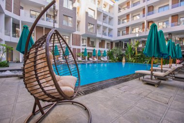 Lüks tropikal apartman otelinde güneşli yataklarla yüzme havuzu.