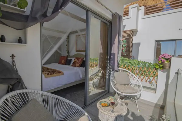 Çift yatak odalı ve veranda kapısı sürgülü, tropikal tatil köyünde lüks bir apartmanın teras balkon mobilyaları.
