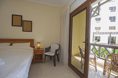 Lüks mobilyaların iç dizayn dekorasyonu ev yatak odasını gösteriyor ve sürgülü cam kapılı ve balkonlu çift kişilik yatak.