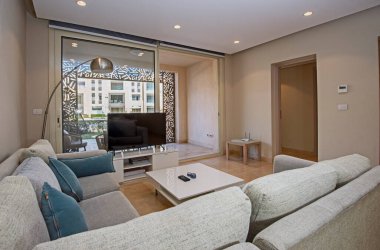 Lüks apartmandaki oturma odasının oturma odası bahçe terası ve havuz manzarasıyla döşenmiş iç tasarım dekorasyonunu gösteriyor.