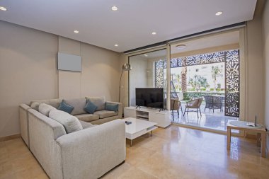 Lüks apartmandaki oturma odasının oturma odası bahçe terası ve havuz manzarasıyla döşenmiş iç tasarım dekorasyonunu gösteriyor.