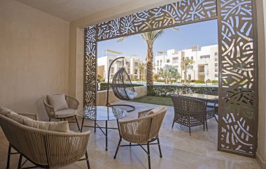 Lüks bir apartman dairesinin bahçe terası. Tropikal bir tatil köyü. Mobilya ve yüzme havuzu manzaralı.