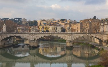Roma 'daki Tiber nehri üzerindeki eski taş kemerli yol köprüsü bulutlu gökyüzü ile Europen şehir merkezi
