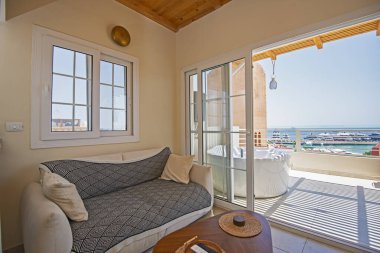 Lüks apartmandaki oturma odası salonu terası ve deniz manzarası ile döşenmiş iç tasarım dekorasyonunu gösteriyor.