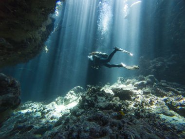 Su altındaki mağaralarda, kaya duvarları ve dalış yapan dalgıçlarla yüzeyden dans eden güneş ışınlarının manzara görüntüsü