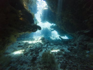 Su altı mağarasında, kaya duvarlarıyla yüzeyden dans eden güneş ışığının manzarası.