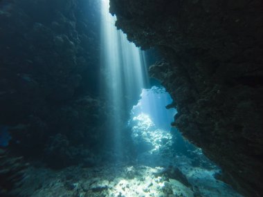 Su altı mağarasında, kaya duvarlarıyla yüzeyden dans eden güneş ışığının manzarası.