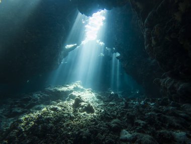 Su altı mağarasında, kaya duvarlarıyla yüzeyden dans eden güneş ışığının manzarası.