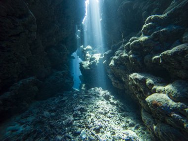Su altı mağarasında, kaya duvarlarıyla yüzeyden dans eden güneş ışığının manzarası.