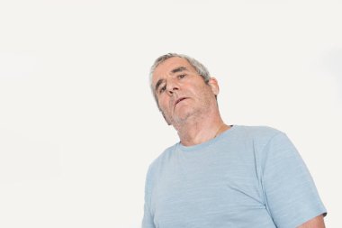 Yaşlı adam sarı arka planda poz veriyor.