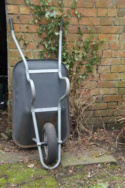 Plastic Wheelbarrow Resting Brick Garden Wall — Stock Photo, Image