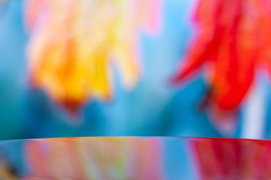 Parlak yüzey, parlak mavi ve sarı renkli soyut arkaplanı yansıtarak büyüleyici ve modern bir reklam kavramı yaratır.