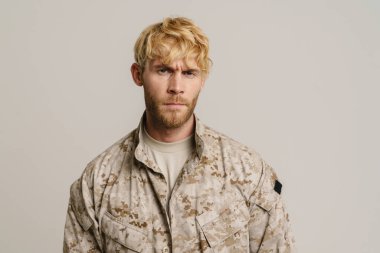 Üniformalı beyaz bir asker beyaz arka planda izole edilmiş kameraya bakıyor.