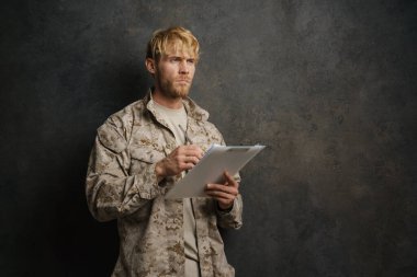 Siyah arka planda izole edilmiş pano ile poz veren üniformalı beyaz bir asker.