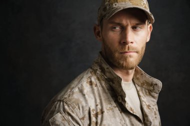 White military man wearing uniform posing and looking aside isolated over black background clipart