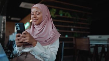 Pozitif Müslüman Afrikalı kadın ofiste telefonla yazıyor.