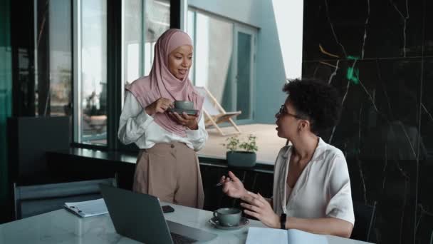 两个漂亮的多种族穆斯林和非洲妇女在办公室里谈论和看笔记本电脑 — 图库视频影像