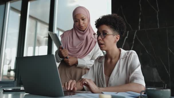 两名集中的多族裔穆斯林和非洲妇女在办公室用笔记本电脑交谈和工作 — 图库视频影像