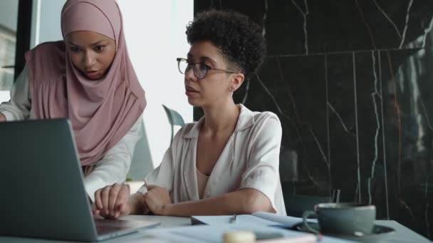 两名严肃的多族裔穆斯林和非洲妇女在办公室用笔记本电脑交谈和工作 — 图库视频影像