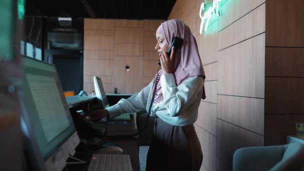Mulher Muçulmana Positiva Recepcionista Fica Recepção Falando Telefone Hotel — Vídeo de Stock