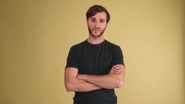 Tişört giyen hoşnutsuz esmer adam sarı stüdyodaki bir şeye katılmıyor.