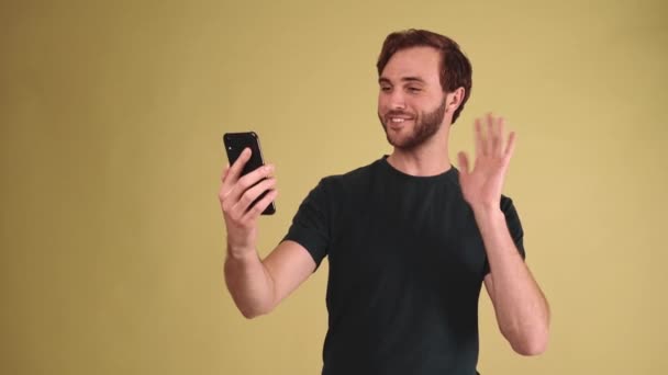 在黄色的工作室里 一个快乐的黑发男人在手机上通过视频通话 — 图库视频影像