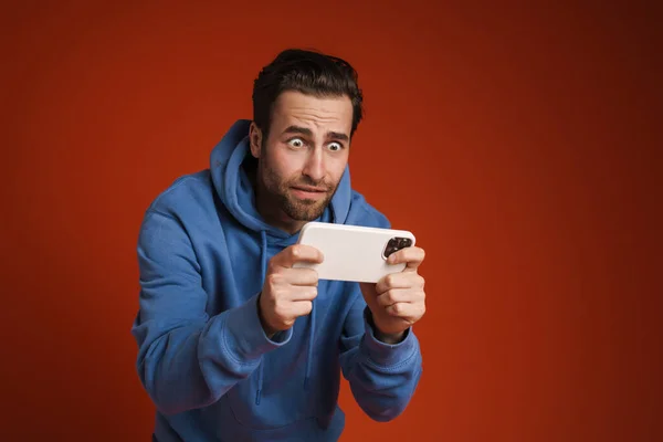 Jonge Geschokte Man Spelen Online Spel Mobiele Telefoon Geïsoleerd Rode — Stockfoto