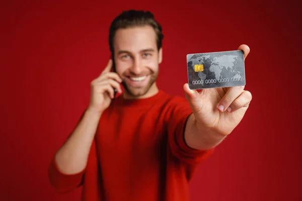 Fiatal Sörte Férfi Beszél Mobilon Miközben Mutatja Hitelkártya Elszigetelt Piros — Stock Fotó