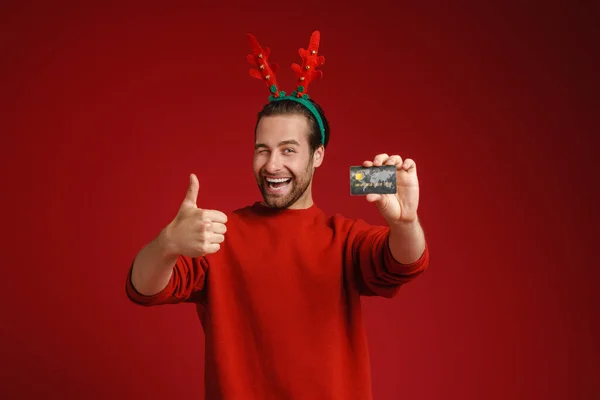 Joven Con Cuernos Venado Navidad Mostrando Tarjeta Crédito Pulgar Hacia —  Fotos de Stock