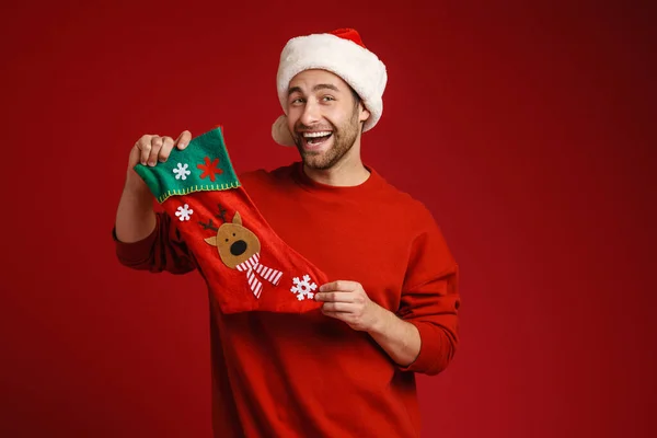모자를 남자가 배경에 크리스마스 양말을 두르고 포즈를 취하며 있습니다 — 스톡 사진